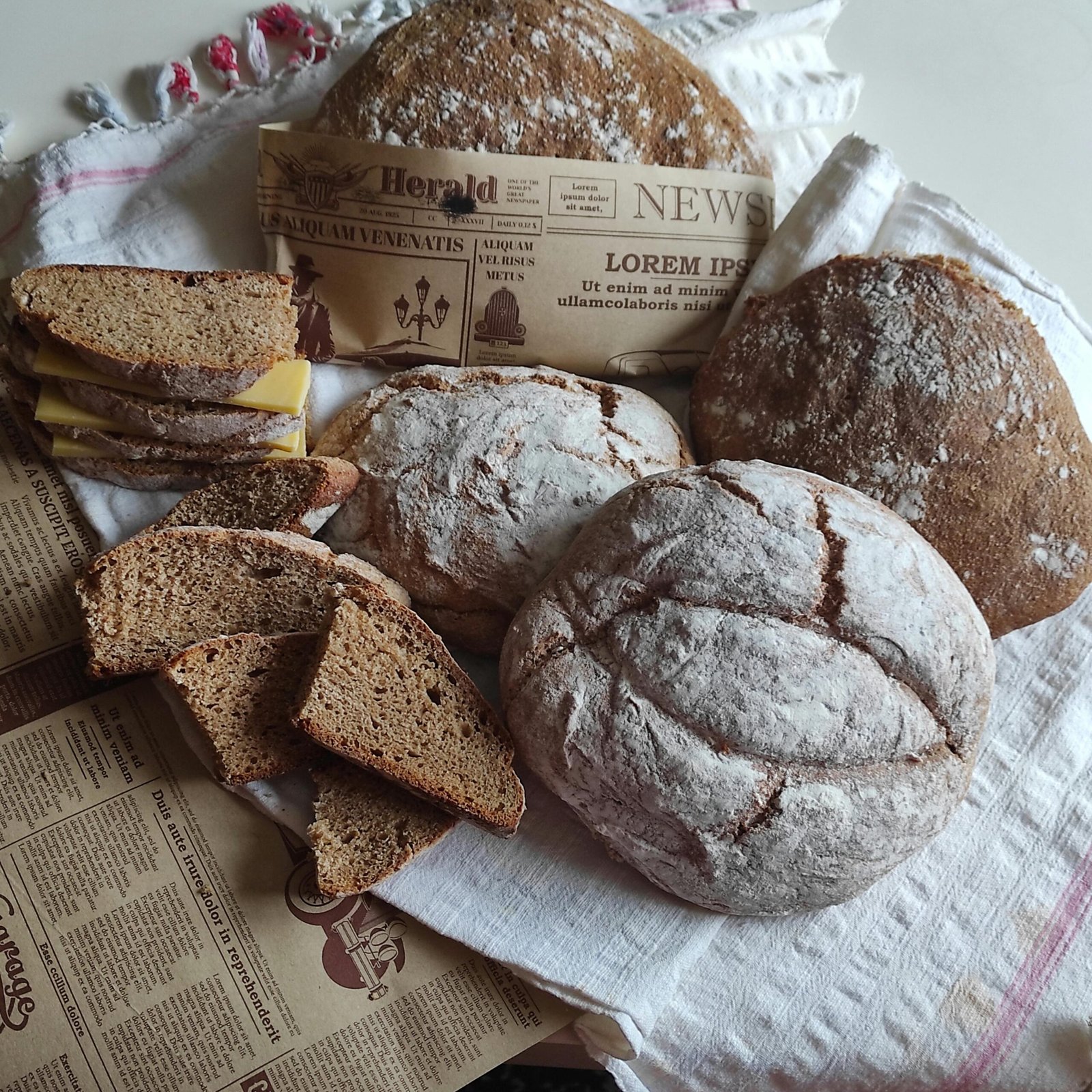 Artistic display of homemade rustic bread alongside vintage newspaper pages.